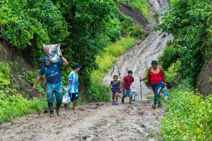 Pobladores caminan extensos tramos, en vía cubierta de lodo.