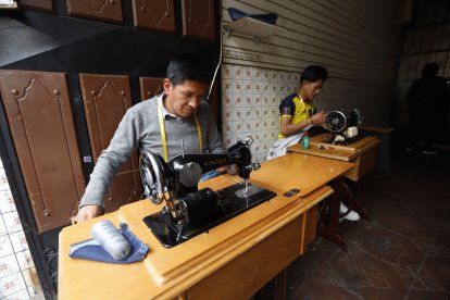Padre e hijo trabajan de domingo a domingo en sus máquinas de coser.