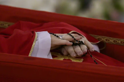 El cuerpo del papa Francisco dentro de su ataúd sosteniendo en sus manos un rosario.