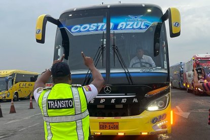 Agente de la CTE comprueba el estado de las luces de un bus de transporte de pasajeros.