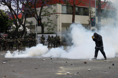 Un manifestante camina a través del humo de granadas de humo aturdidoras .