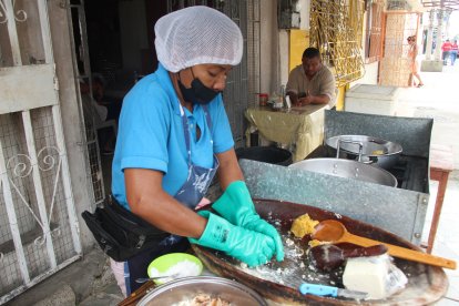 Doña Gaby usa una paila de madera para majar el verde y mezclarlo .