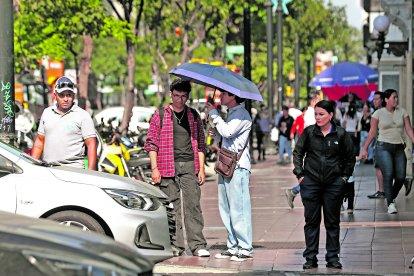 Ciudadanos se cubren con un parasol del intenso sol.