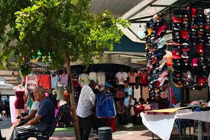Un vendedor informal ofrece ropa justo frente a locales establecidos dedicados al mismo rubro.