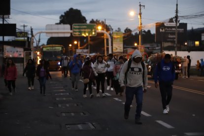 Trabajadores caminando largas distancias en el kilómetro 45 de la vía Tabacundo-Cajas, afectados por el bloqueo vial durante el Paro Nacional en Ecuador.