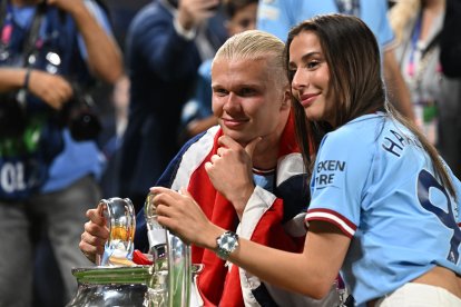 Manchester City's Norwegian striker #9 Erling Haaland poses with the European Cup trophy flanked by Isabel Haugseng Johansen (R) as he celebrates winning the UEFA Champions League final football match between Inter Milan and Manchester City at the Ataturk Olympic Stadium in Istanbul, on June 10, 2023. Manchester City won the match 1-0. (Photo by Paul ELLIS / AFP)