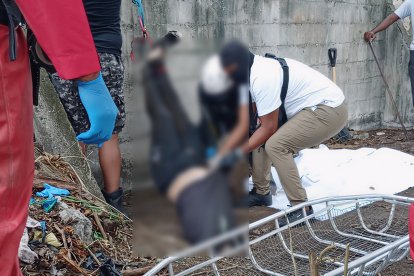 Agentes de la Policía y del Cuerpo de Bomberos extraen un cuerpo de la cisterna ubicada en el barrio Vista al Mar, dentro de una escuela abandonada.