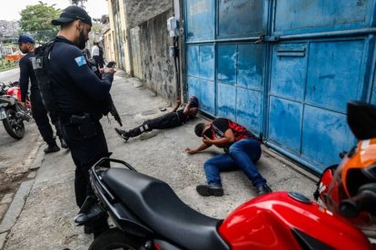 Dos hombres son custodiados por agentes de la Policía de Río durante el mega operativo.