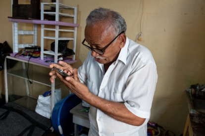 Víctor Guarín mientras mira su teléfono con ayuda de unos lentes, pero con una escasa visión.