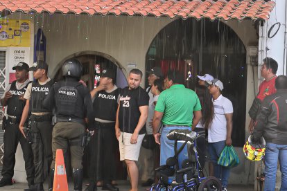 Agentes policiales y vecinos se congregan bajo la lluvia en el barrio San Francisco, tras el ataque armado que dejó un hombre muerto y un niño herido.