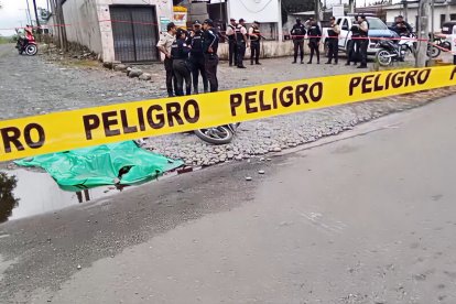 Agentes policiales acordonan la escena donde un hombre fue asesinado a tiros en La Concordia; la motocicleta quedó junto al cuerpo, cubierto por una lona verde.