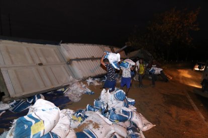 Trabajadores descargan sacos de alimento para camarón del tráiler siniestrado.
