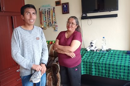 Bryan posa junto a su madre, Patricia Bazurto, mientras sostiene uno de los zapatos de competencia que compró hace cinco años con sus propios ahorros.