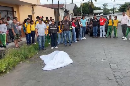 Estudiantes y docentes rodean el cuerpo de la profesora Diana Alcívar, asesinada a pocos metros del colegio donde laboraba.