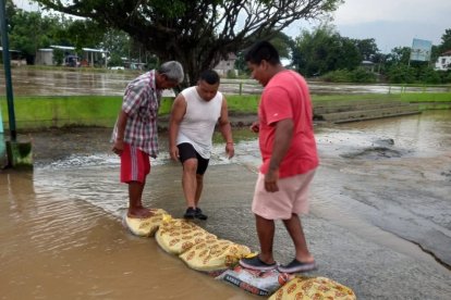 Pobladores de la parroquia Vernaza colocan sacos con arena para tratar de contener el agua.