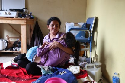 Mayra Canales sostiene a su hija, en el interior de su vivienda en Bastión Popular.