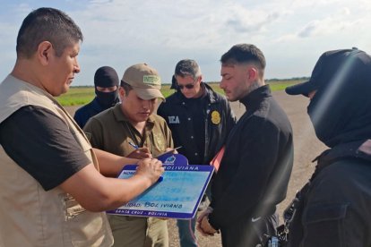 Fotografía de la Policía de Bolivia sobre el uruguayo Sebastián Marset (c) antes de abordar un avión tras su captura en Santa Cruz (Bolivia).