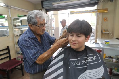 Don Jorge Barros le corta el cabello a Nicolás, quien prefiere la tijera frente a las tendencias actuales.