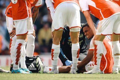 Jurriën Timber se toca la pierna con claros gestos de dolor mientras es atendido por el cuerpo médico del Arsenal