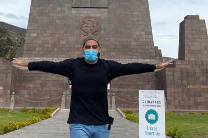 Un turista con el monumento de la Mitad del Mundo de fondo.