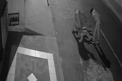 3. Los dos tipos desvalijan a la víctima tendida en el suelo.