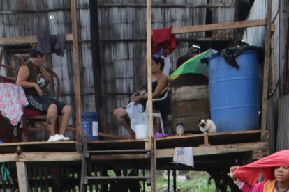 Un joven lava sus zapatos. Atrás la familia Villavicencio, quienes se quedaron sin paredes.