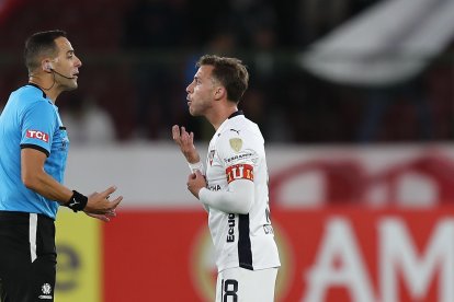 Lucas Piovi (d) de LDU discute con el árbitro Esteban Ostojich.