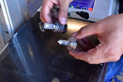Un mecánico muestra la diferencia física entre un foco de tecnología LED (arriba) y un foco tradicional, halógeno.