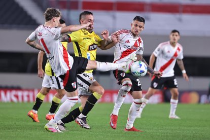 Facundo Colidio (i) de River disputa el balón con Octavio Rivero (c) de Barcelona.