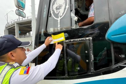 Agente de tránsito revisa los documentos del conductor de un bus.