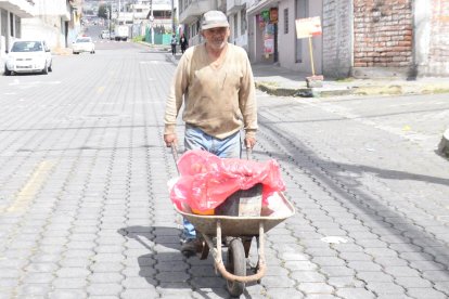 Adultos mayores se ayudan con carretillas para llevar los baldes de agua a sus casas.