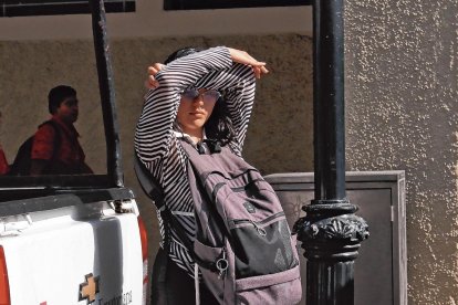 Los peatones se cubren con lo que pueden del cegador resplandor vespertino.