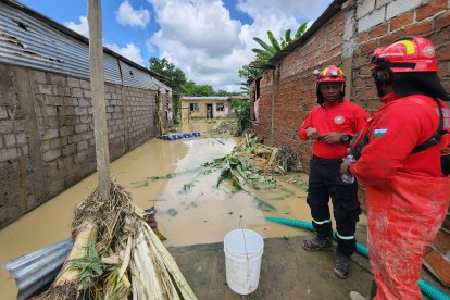 Dos miembros de equipos de emergencia inspeccionan una zona anegada en Esmeraldas, tras la fuerte lluvia que dejó calles cubiertas de agua y escombros.