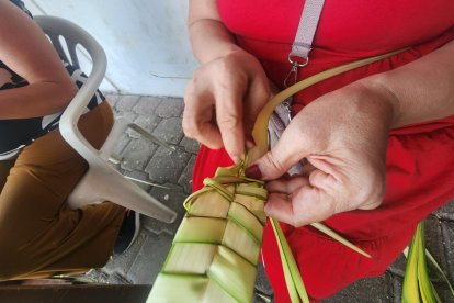 Manos devotas entrelazan las hojas de palma en delicados tejidos, dando forma a los ramos.