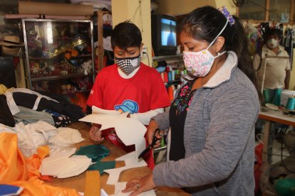 Elvis ayuda a su madre a elaborar las mascarillas para costear sus medicamentos y ahorrar un poco de dinero.