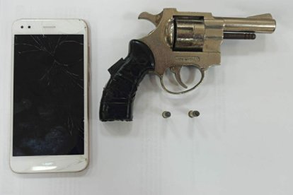 El arma de fuego y el celular que fue hallado en poder de los detenidos.