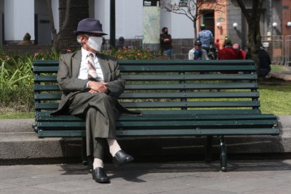 En la Plaza Grande, un hombre con mascarilla descansa en una de sus bancas.