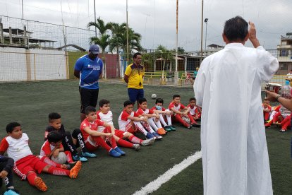 Edison Maldonado, Víctor Araujo y los pequeños de la escuela reciben la bendición antes de comenzar a entrenar.