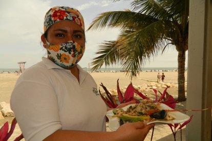 Elisa González muestra la langosta al ajillo en salsa de mariscos, el plato estrella.