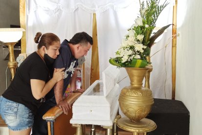 Miguel y Jéssica contemplan el ataúd donde reposan los restos de su ser querido.