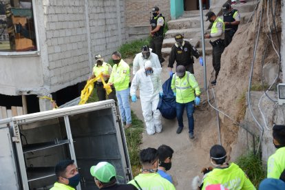 Agentes de Medicina Legal cargan el cadáver de la víctima hacia la ambulancia.