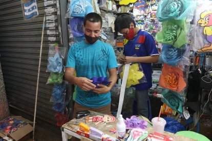 Washington junto a su hijo, a quien le enseña a elaborar las manualidades. Con él atiende en el negocio.