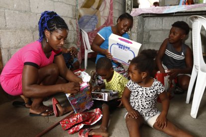 Los niños se sentaron en el piso para abrir los obsequios. Su progenitora los ayudó a romper el papel de regalo.