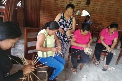 Con gran agilidad, Martha Tanguila da forma a un pequeño canasto.