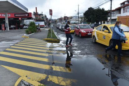 Los transeúntes sortean las cochas de agua que se forman en los  huecos del asfalto deteriorado.