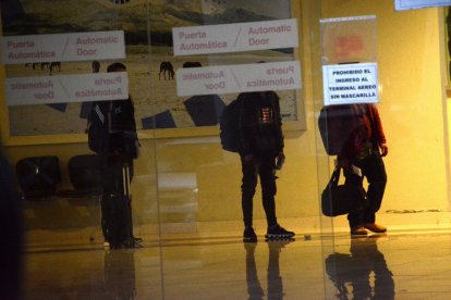 Los viajeros se despiden de sus familiares desde la sala de embarque.