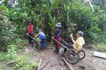 Con dos maderos sujetan las sillas de ruedas y hacen los recorridos guiados.