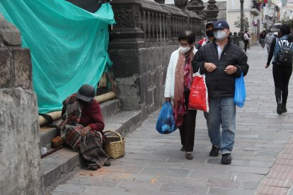Afuera de la Catedral, una mujer de la tercera edad espera la caridad.