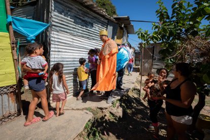 Hombres vestidos de Reyes Magos saludan a los niños en un caserío dentro del Cementerio General del Sur, hoy, en Caracas (Venezuela). En Venezuela, los Reyes Magos atravesaron este miércoles, 6 de diciembre, el principal cementerio público del país para llevar la alegría de sus colores y regalos a más de 80 niños de una comunidad olvidada en la que los recibieron con los pies descalzos y sonrisas eufóricas. Ni siquiera las cruces, lápidas, coronas de flores y todo el mármol gris del Cementerio General del Sur apagaban los colores de las capas de los tres Reyes Magos que caminaron, junto a un grupo de voluntarios, parte de las 240 hectáreas del lugar para llegar a Barrio Nuevo, una comunidad del oeste de Caracas que se estableció dentro de los linderos de este camposanto. EFE/ Rayner Peña R.
