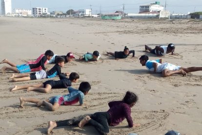 Víctor dirige una clase de surf en la playa antes de ingresar al mar.